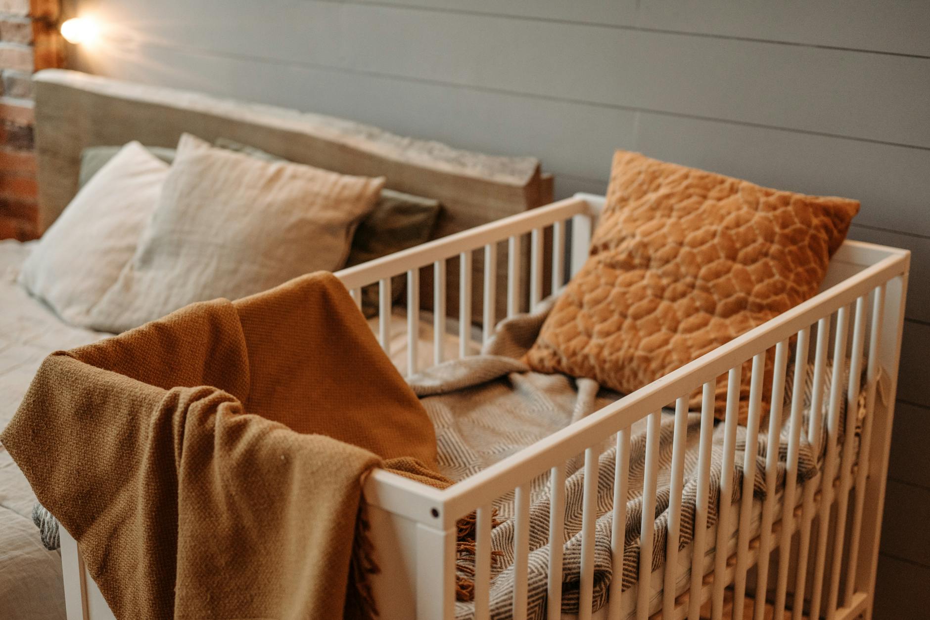 brown blanket and pillow on white wooden crib